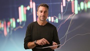 Gert Hansen foran røde og grønne grafer over aktier på blå baggrund